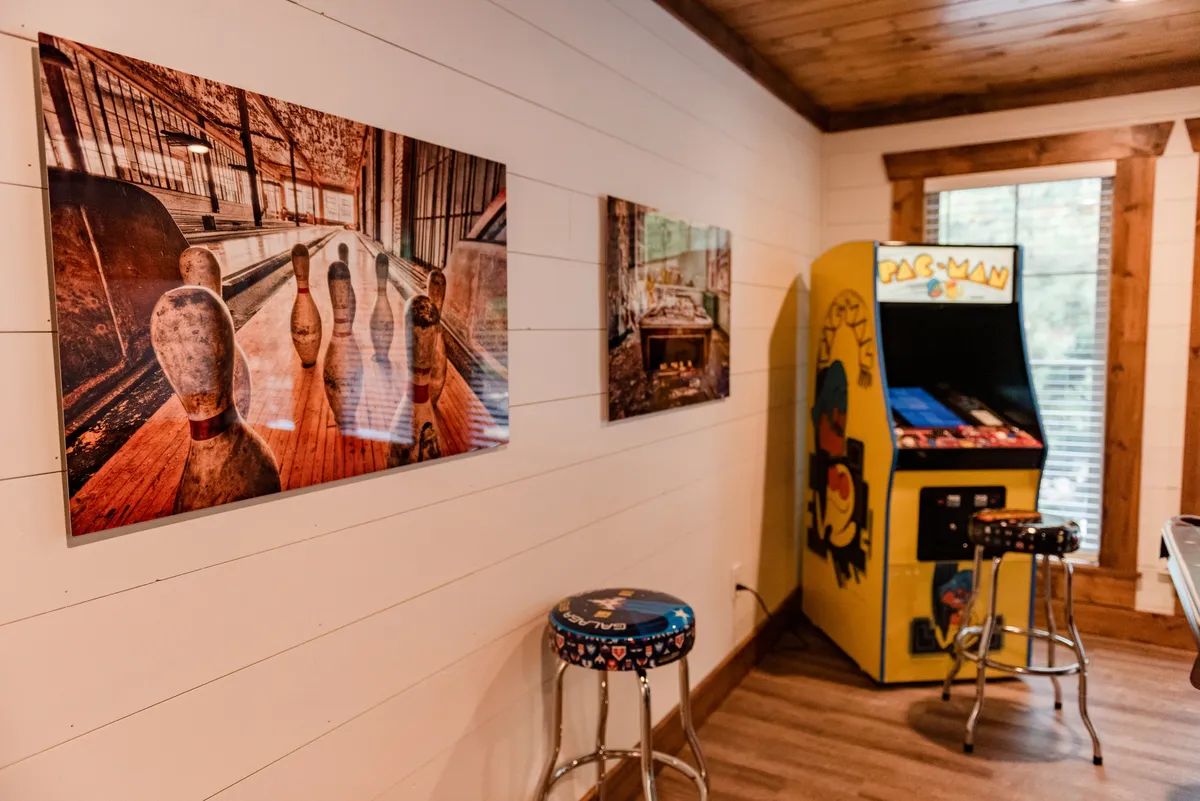 A bright entertainment area with a Pac-Man arcade machine, bowling pin artwork, and colorful bar stools, designed for group gatherings and fun competitions. The decor is playful and encourages both gaming and relaxed conversation.