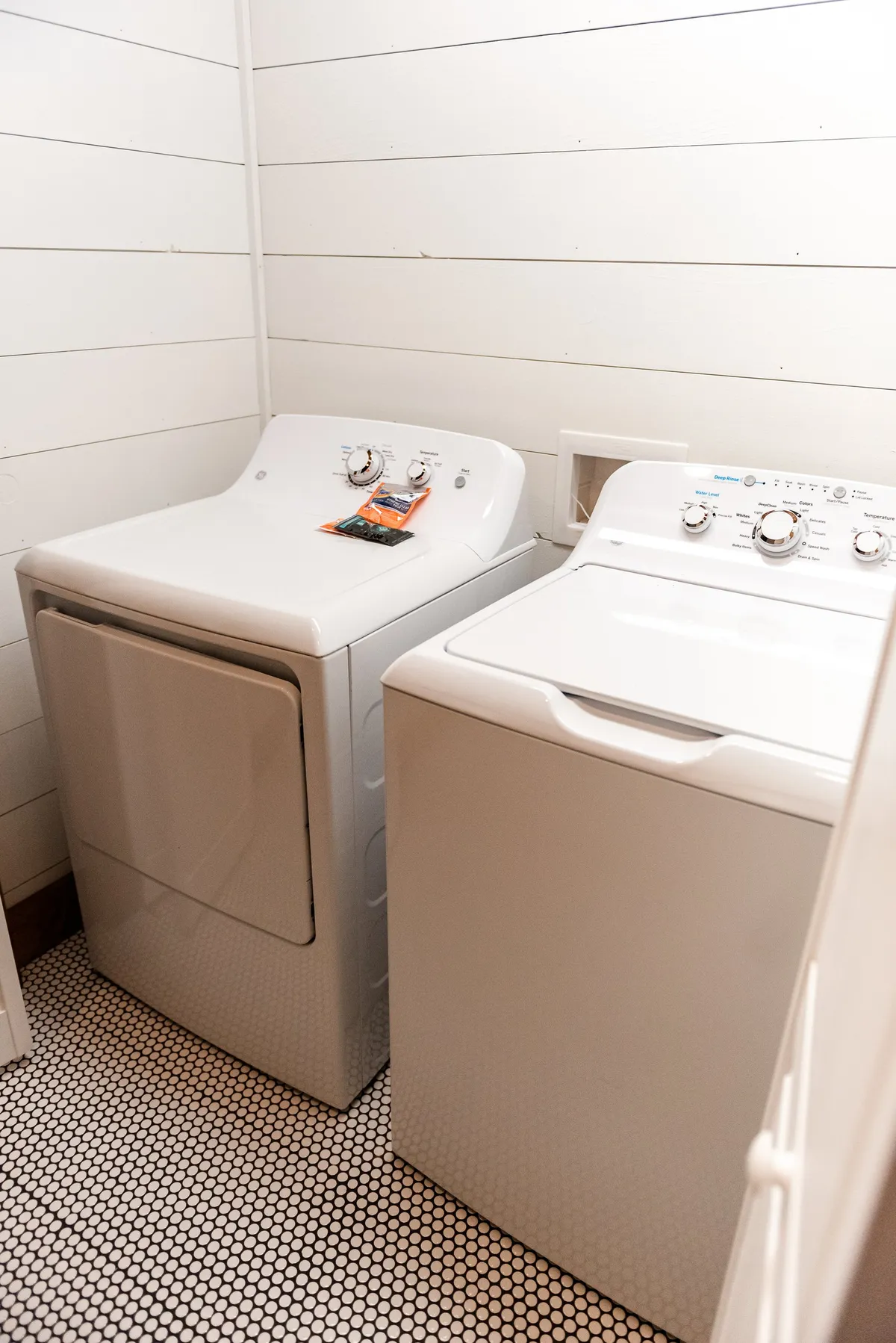 A practical laundry nook featuring a modern washer and dryer atop stylish patterned tiles. The compact design adds convenience, making it easy for families and groups to handle laundry tasks during their stay.