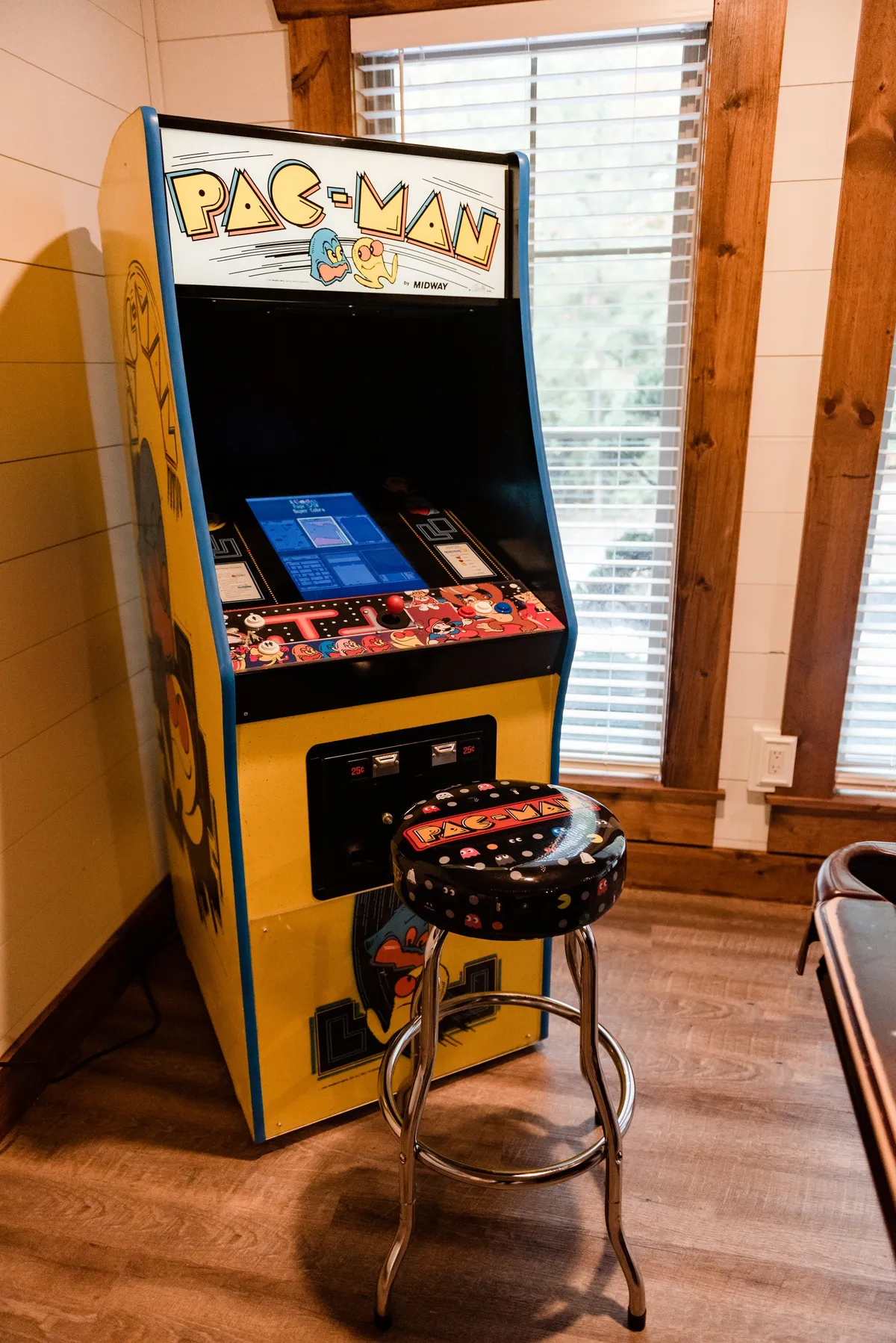 A close-up of the Pac-Man arcade machine with a colorful stool, inviting guests to relive classic gaming excitement. The background hints at a lively, social atmosphere perfect for all ages.