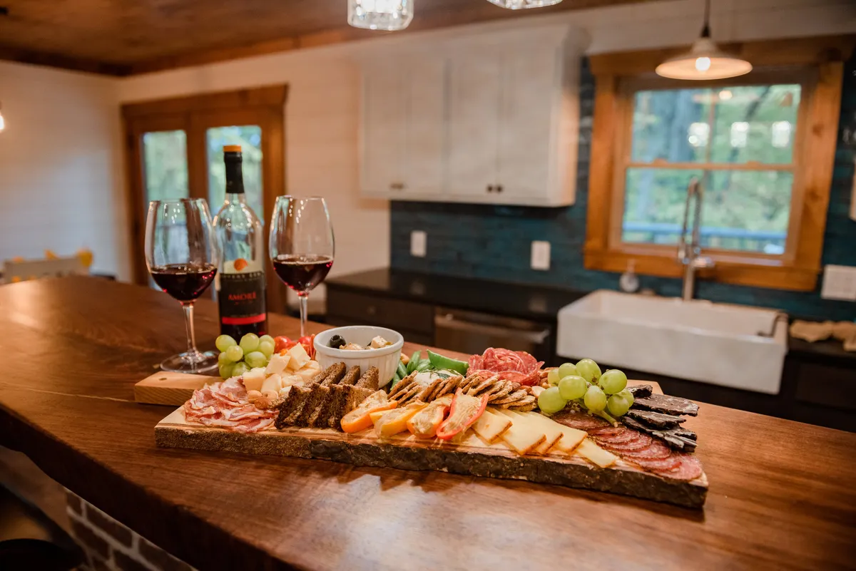 An inviting kitchen scene with a charcuterie board, wine glasses, and bottled wine set out on the counter, suggesting a setting perfect for gatherings, brunches, and shared meals. The inviting lighting and setup evoke the joy of communal dining and celebration.