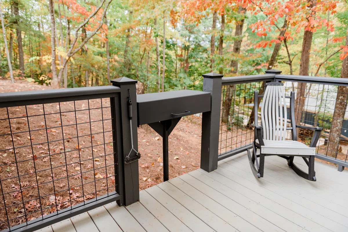A serene wooden deck features a reclining chair looking out over lush trees. The deck feels peaceful and connected to the outdoors, offering a perfect space for relaxing after a day of adventure in the Smoky Mountains or for morning coffee while planning the day's fun.