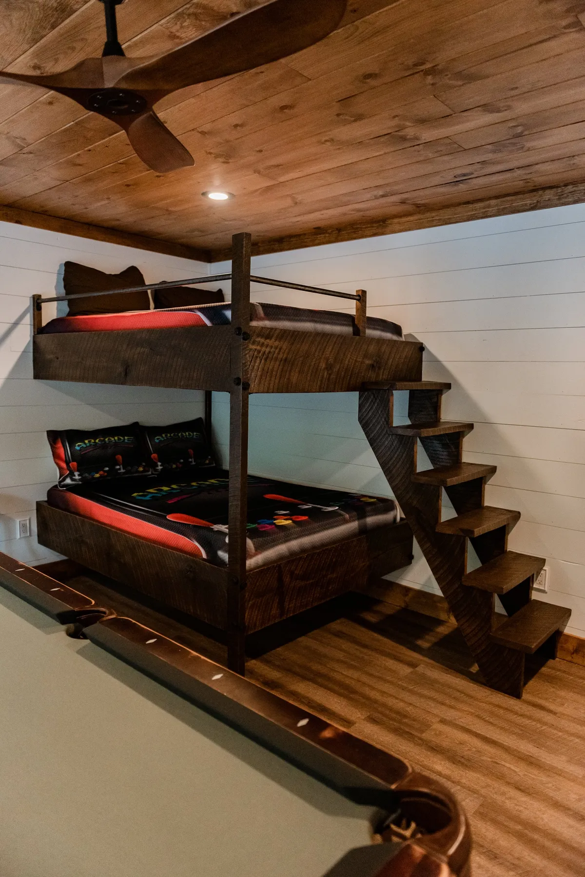 A playful interior scene highlighting stacked bunk beds adjacent to a pool table, bathed in warm, inviting lighting. The setup suggests an area designed for both sleepovers and spirited game nights, ideal for families and groups.